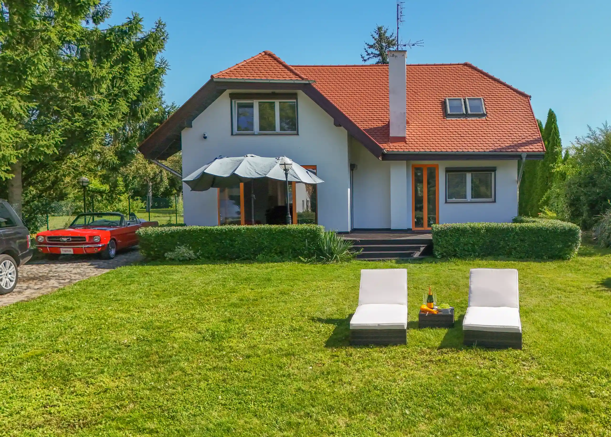 Widok na rezydencję od strony ogrodu z trawą i drzewami